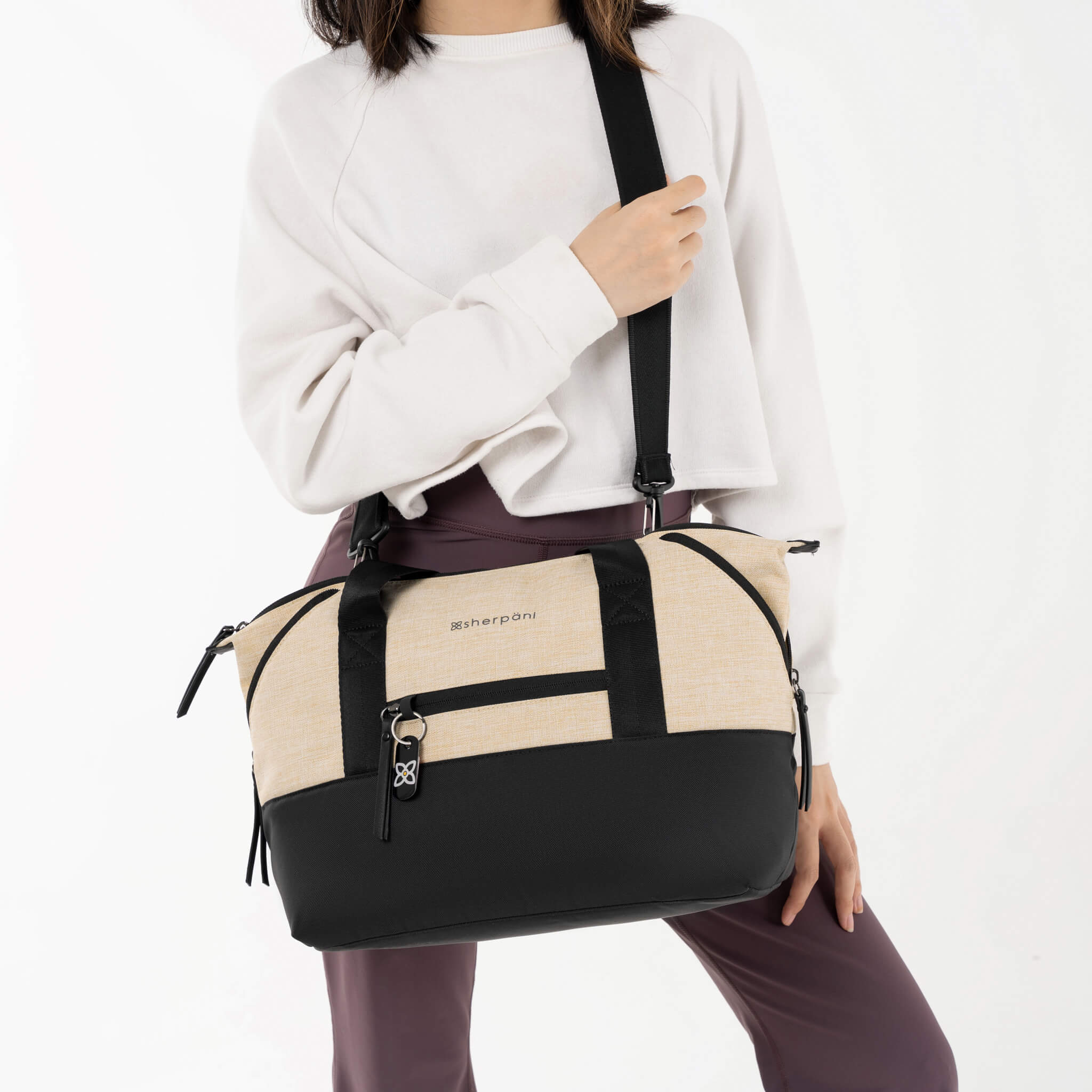 A model using the adjustable crossbody strap to wear the Eclipse in Straw as a crossbody travel purse. 