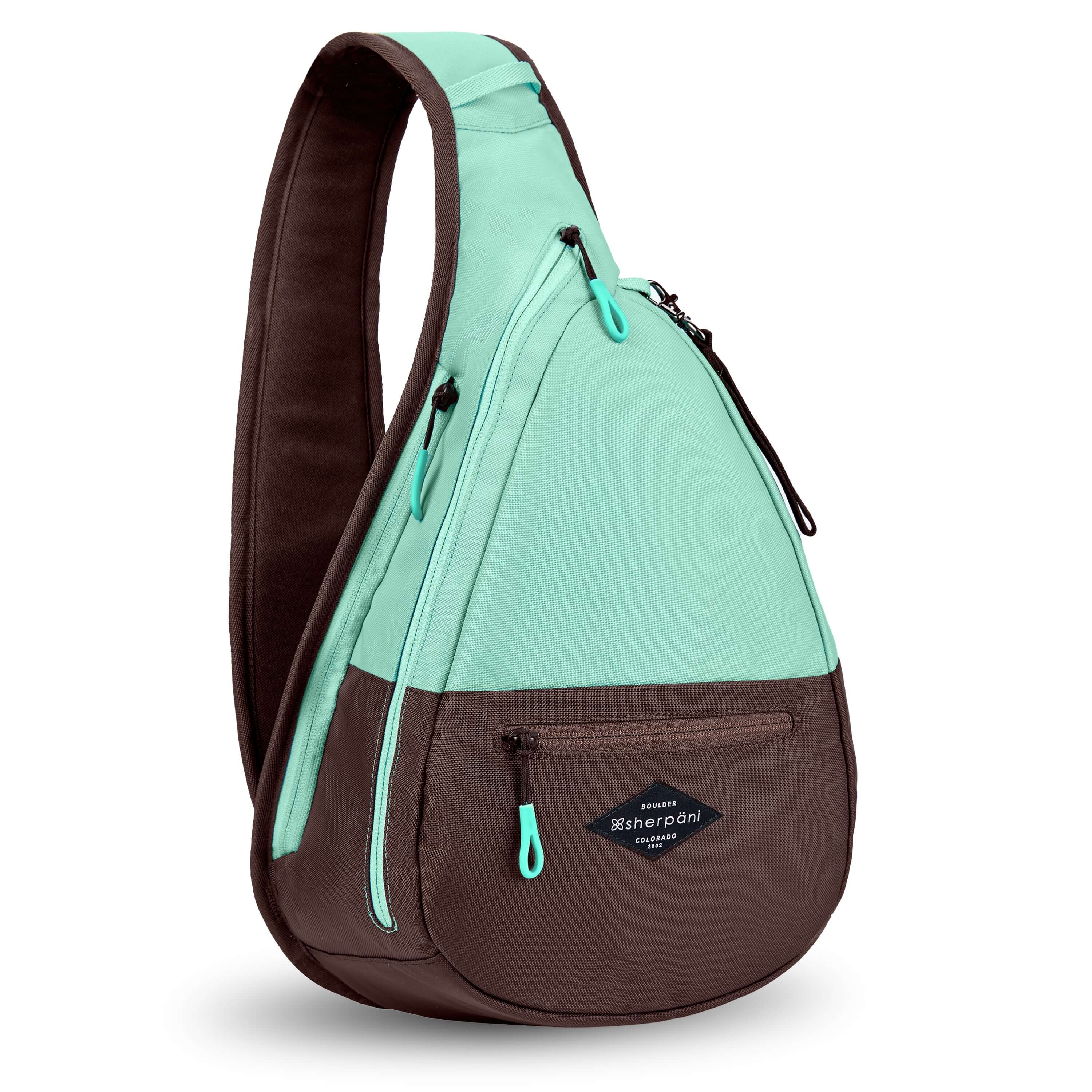Angled front view of Sherpani's bag, the Esprit in Seagreen. The teardrop shaped bag is two-toned in light green and brown. There is a small zipper pocket on the front of the bag, the main zipper compartment in the middle, and another zipper pocket towards the back of the bag. It has easy-pull zippers accented in light green. A branded Sherpani keychain is clipped to a fabric loop near the top of the bag. 