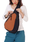 Close up view of a dark haired model facing the camera. She is wearing a white shirt, blue pants and Sherpani’s Anti-Theft bag, the Esprit AT in Copper, as a crossbody.
