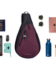 Top view of example items to fill the bag. Sherpani’s Anti-Theft bag, the Esprit AT in Merlot, lies in the center. It is surrounded by an assortment of items: Sherpani travel accessories the Barcelona in Seagreen and the Poet in Stone, car key, passport, sunglasses, iPad, water bottle, phone.