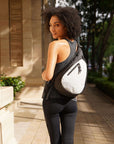 Close up view of a curly haired model facing away from the camera and smiling over her left shoulder. She is wearing a gray tank top, black leggings and Sherpani’s Anti-Theft bag, the Esprit AT in Sterling, across her back.