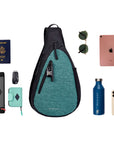 Top view of example items to fill the bag. Sherpani’s Anti-Theft bag, the Esprit AT in Teal, lies in the center. It is surrounded by an assortment of items: Sherpani travel accessories the Barcelona in Seagreen and the Poet in Stone, car key, passport, sunglasses, iPad, water bottle, phone.