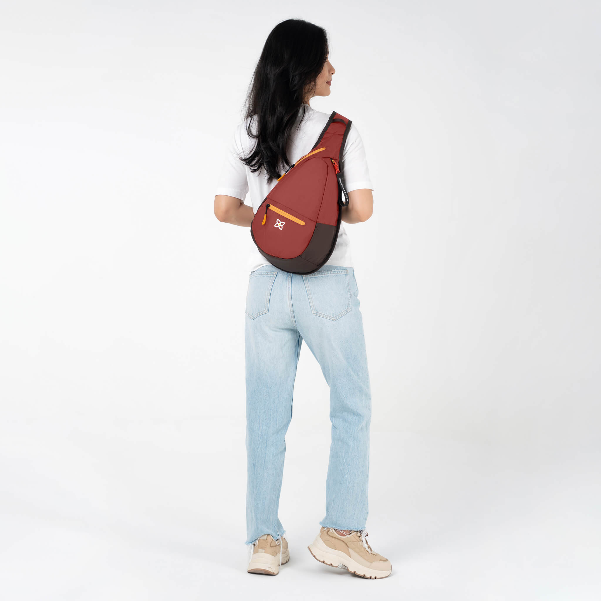 A model wearing Sherpani sling backpack for women's travel, the Esprit in Cider. 