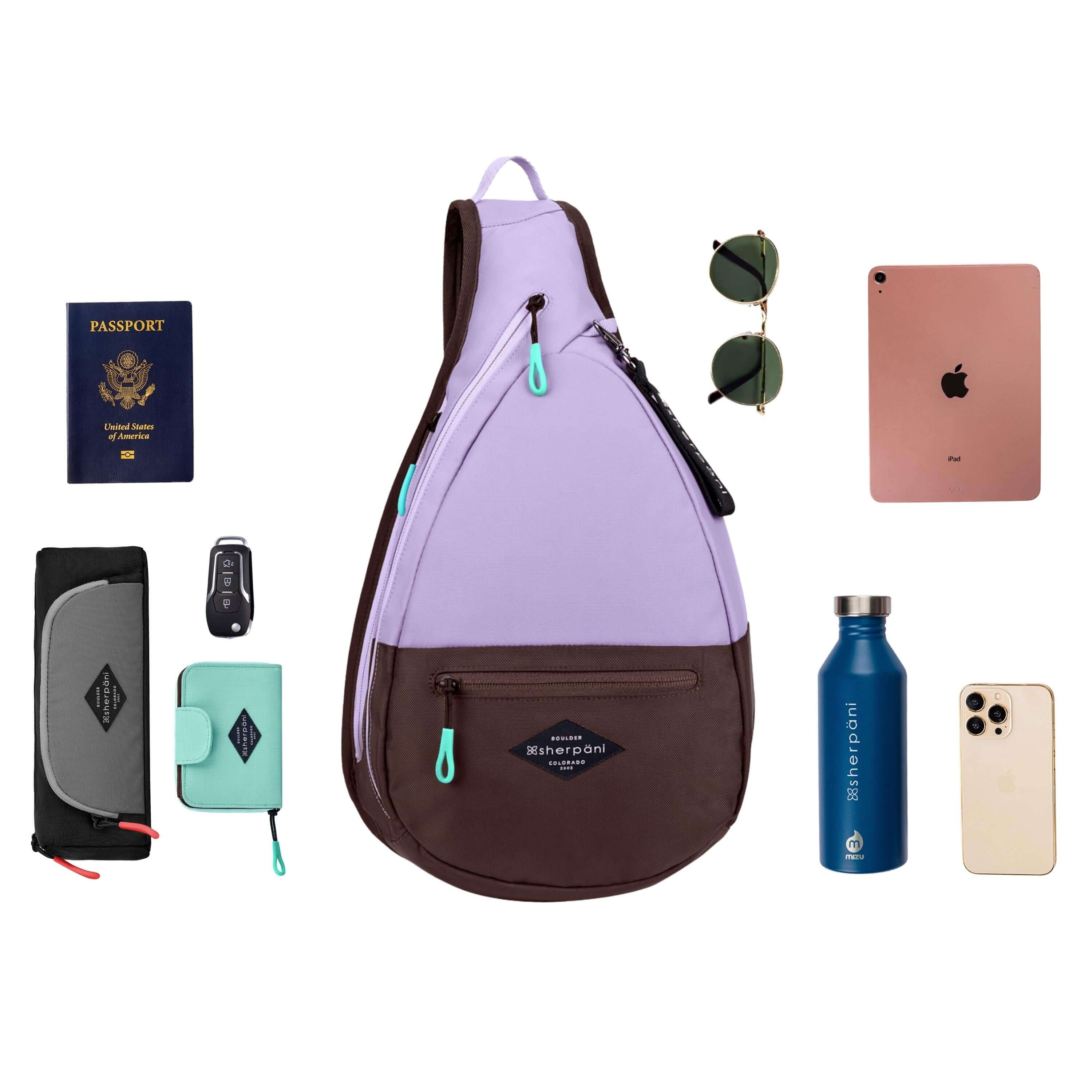Top view of example items to fill the back. Sherpani's bag, the Esprit in Lavender, lies in the center. It is surrounded by an assortment of items: passport, car key, sunglasses, tablet, water bottle, phone and Sherpani travel accessories the Poet in Stone and the Barcelona in Seagreen. 