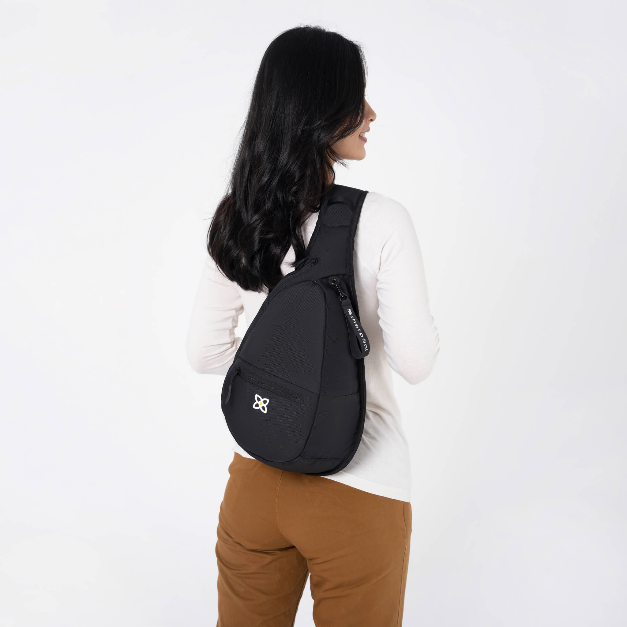 A model wearing the Esprit in Raven, a sling style backpack built for women's travel. 