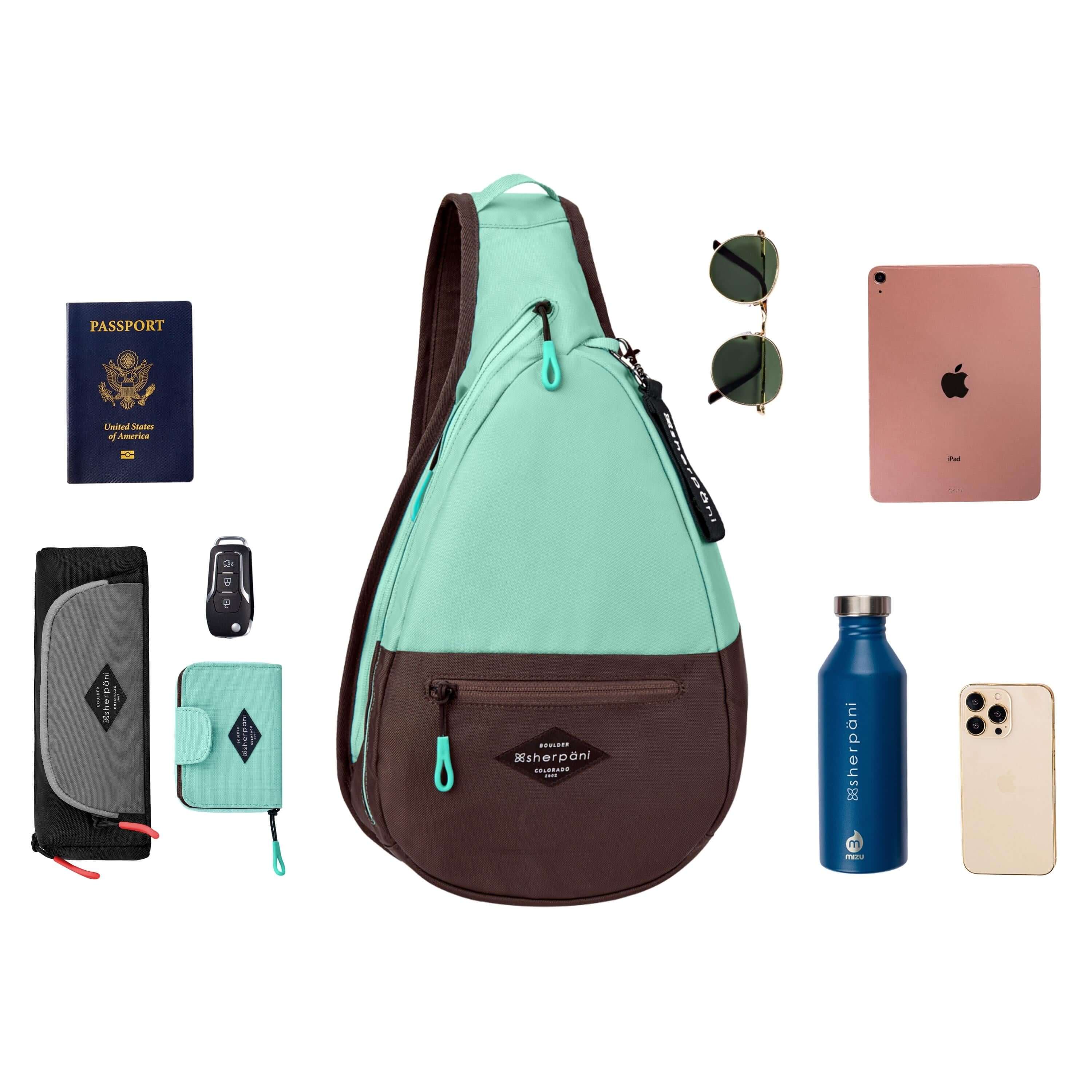 Top view of example items to fill the back. Sherpani's bag, the Esprit in Seagreen, lies in the center. It is surrounded by an assortment of items: passport, car key, sunglasses, tablet, water bottle, phone and Sherpani travel accessories the Poet in Stone and the Barcelona in Seagreen. 