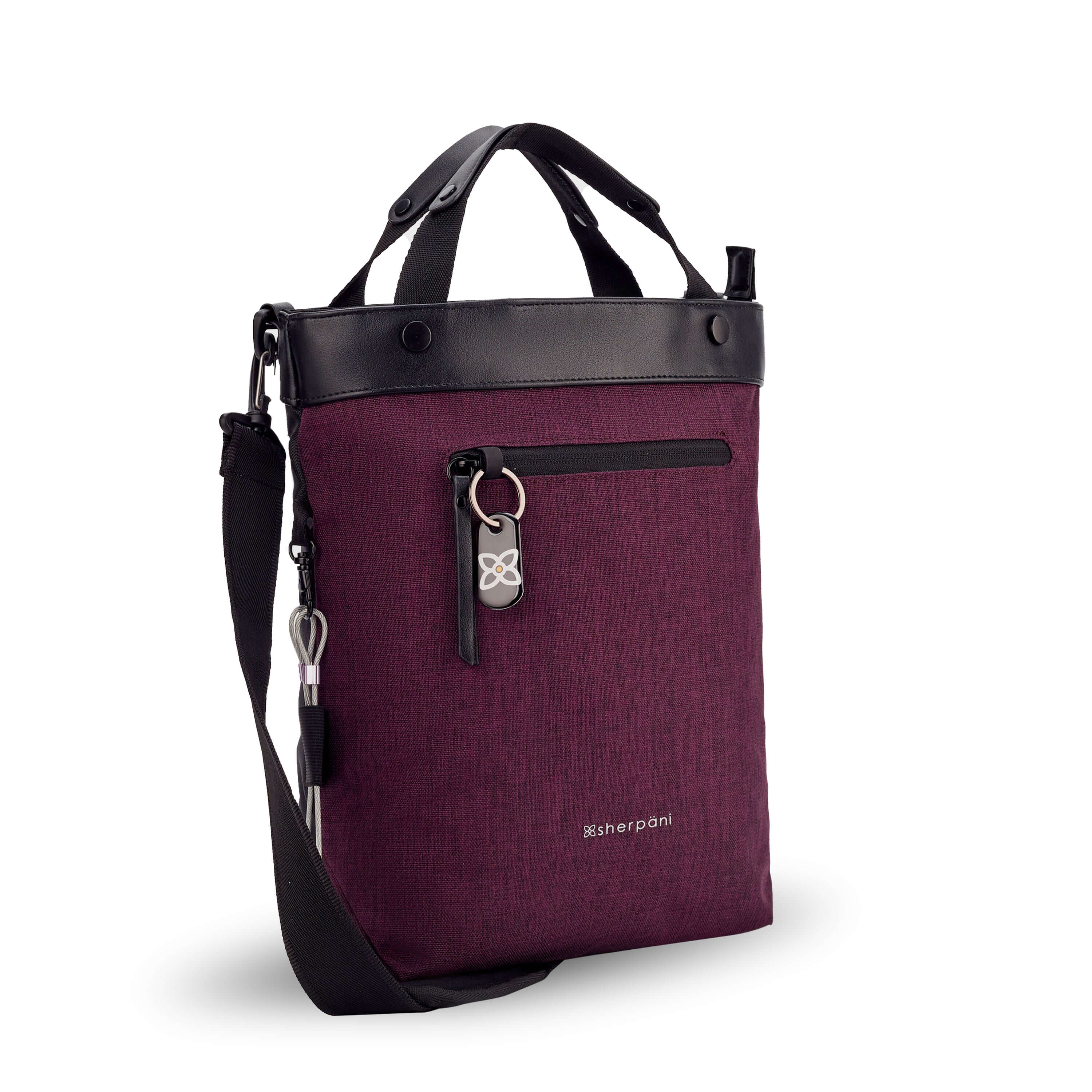 Angled front view of Sherpani's Anti-Theft bag, the Geo AT in Merlot, with vegan leather accents in black. The bag features short tote handles and an adjustable/detachable crossbody strap. There is a locking zipper compartment on the front with a ReturnMe tag. A chair loop lock is clipped to the side and secured in place by an elastic tab. 