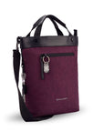 Angled front view of Sherpani's Anti-Theft bag, the Geo AT in Merlot, with vegan leather accents in black. The bag features short tote handles and an adjustable/detachable crossbody strap. There is a locking zipper compartment on the front with a ReturnMe tag. A chair loop lock is clipped to the side and secured in place by an elastic tab.