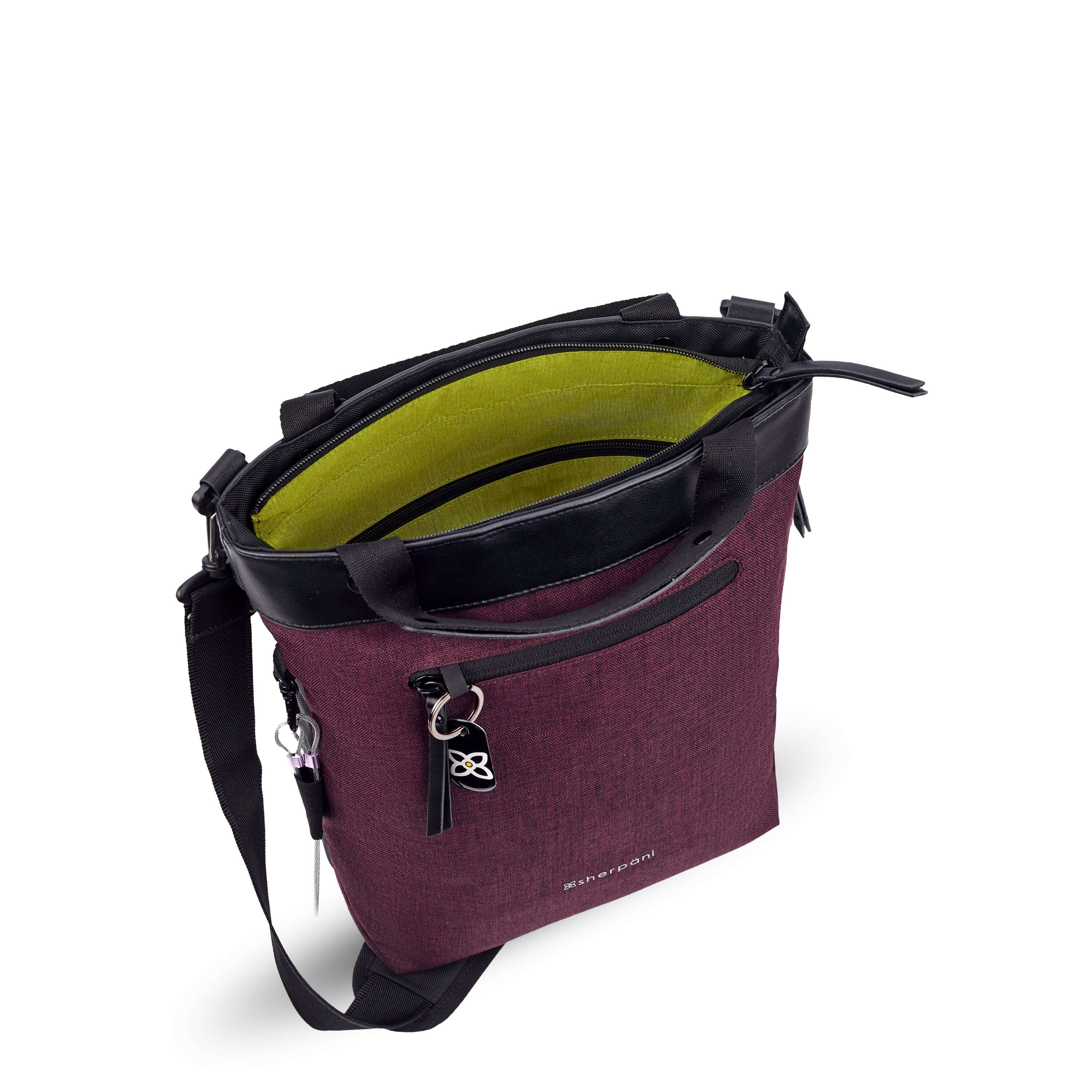 Top view of Sherpani’s Anti-Theft bag, the Geo AT in Merlot, with vegan leather accents in black.The main zipper compartment of the bag is open to reveal a lime green interior. 