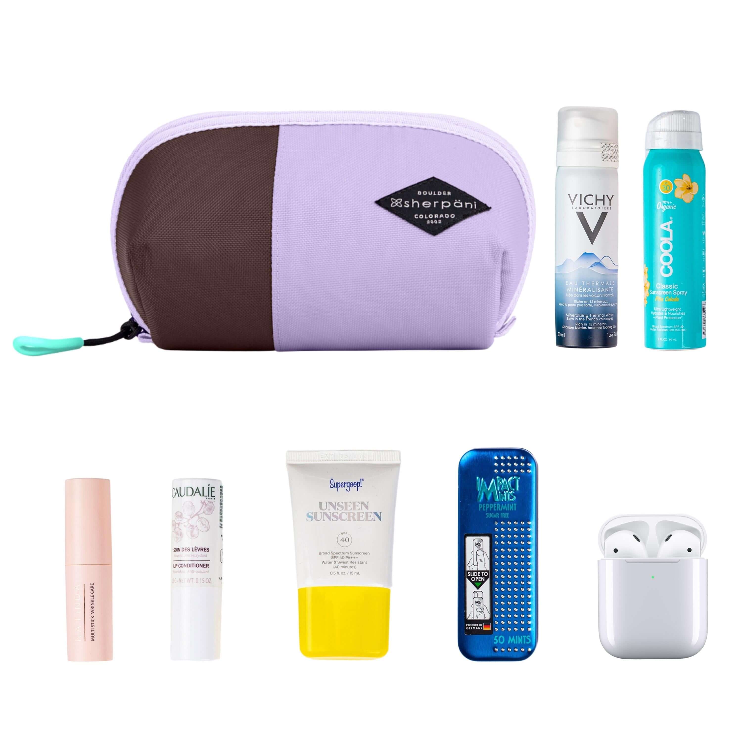 Top view of example items to fill the bag. Sherpani travel accessory, the Harmony in Lavender, is shown in the upper left corner. It is surrounded by an assortment of items: beauty products, skincare products, sunscreen, mints and AirPods.