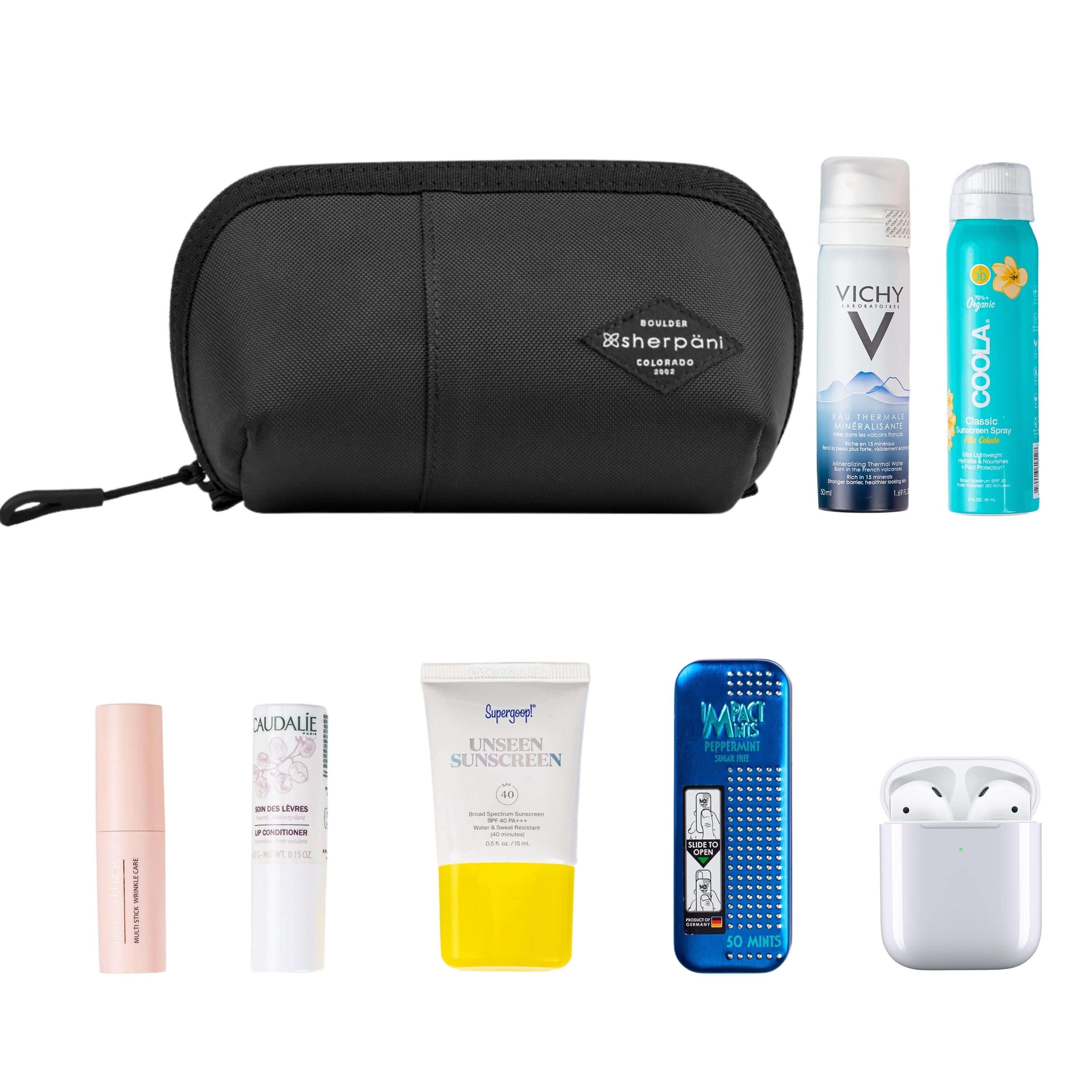 Top view of example items to fill the bag. Sherpani travel accessory, the Harmony in Raven, is shown in the upper left corner. It is surrounded by an assortment of items: beauty products, skincare products, sunscreen, mints and AirPods.