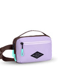 Angled front view of Sherpani’s fanny pack, the Hyk in Lavender. The bag is two-toned, the front half is lavender and the back half is brown. There is an external zipper pocket on the front of the bag. Easy-pull zippers are accented in aqua. The fanny pack features an adjustable strap with a buckle.