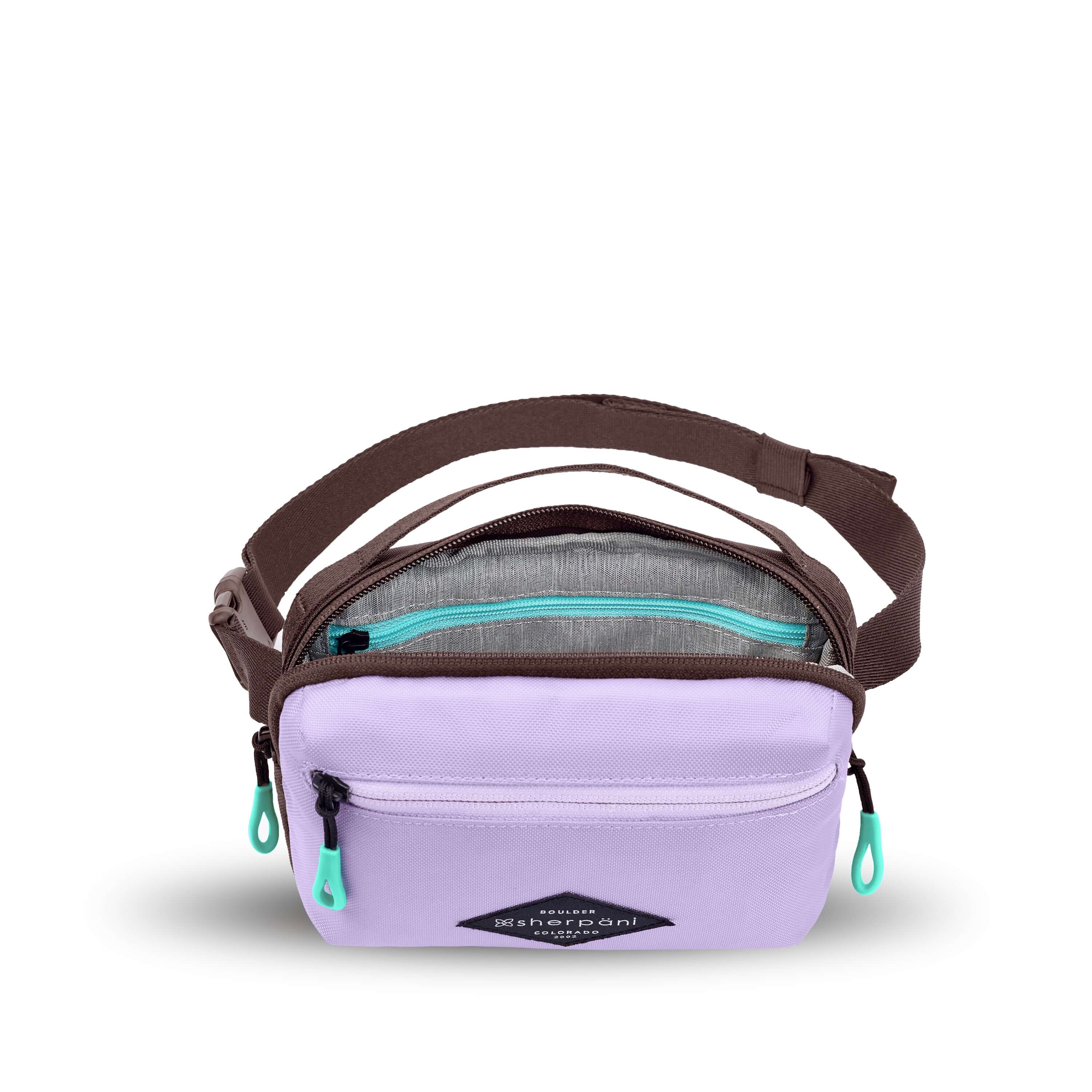 Top view of Sherpani's fanny pack, the Hyk in Lavender. The main zipper compartment is open to reveal a light gray interior and an internal zipper pocket. 