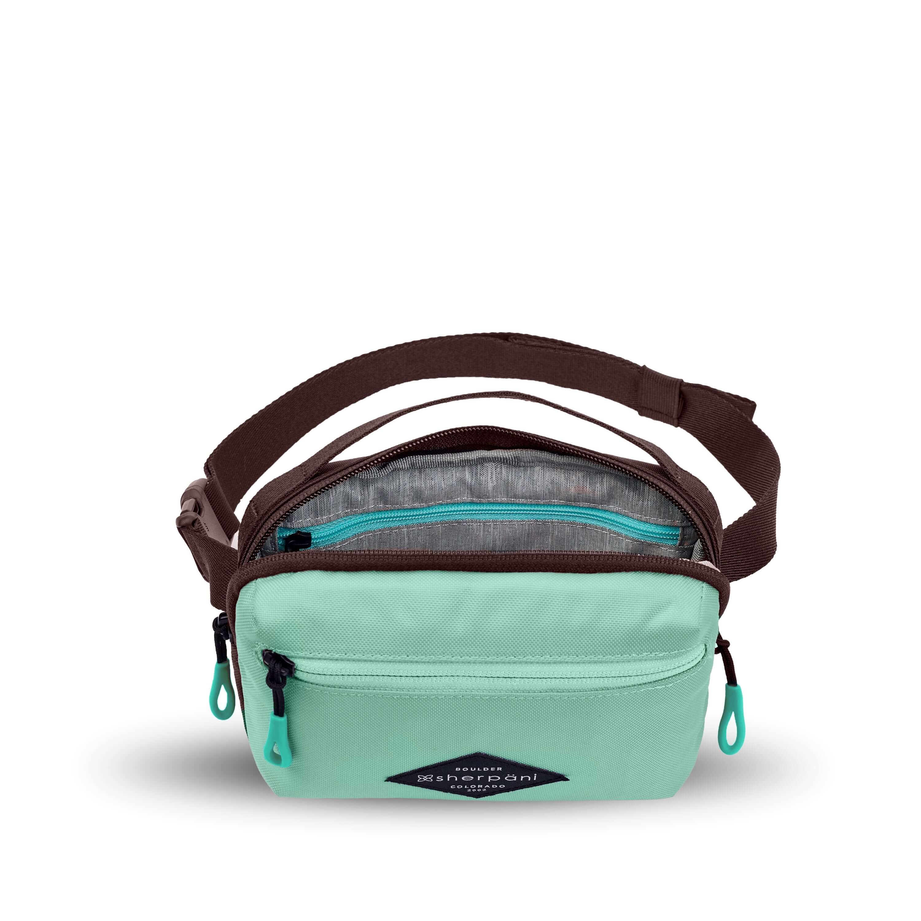 Top view of Sherpani's fanny pack, the Hyk in Seagreen. The main zipper compartment is open to reveal a light gray interior and an internal zipper pocket. 
