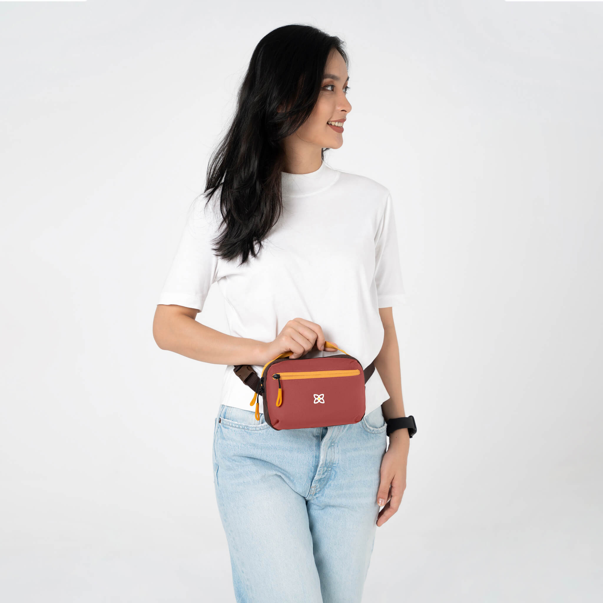 A model wearing Sherpani mini travel purse, the Hyk in Cider, as a waist pack.