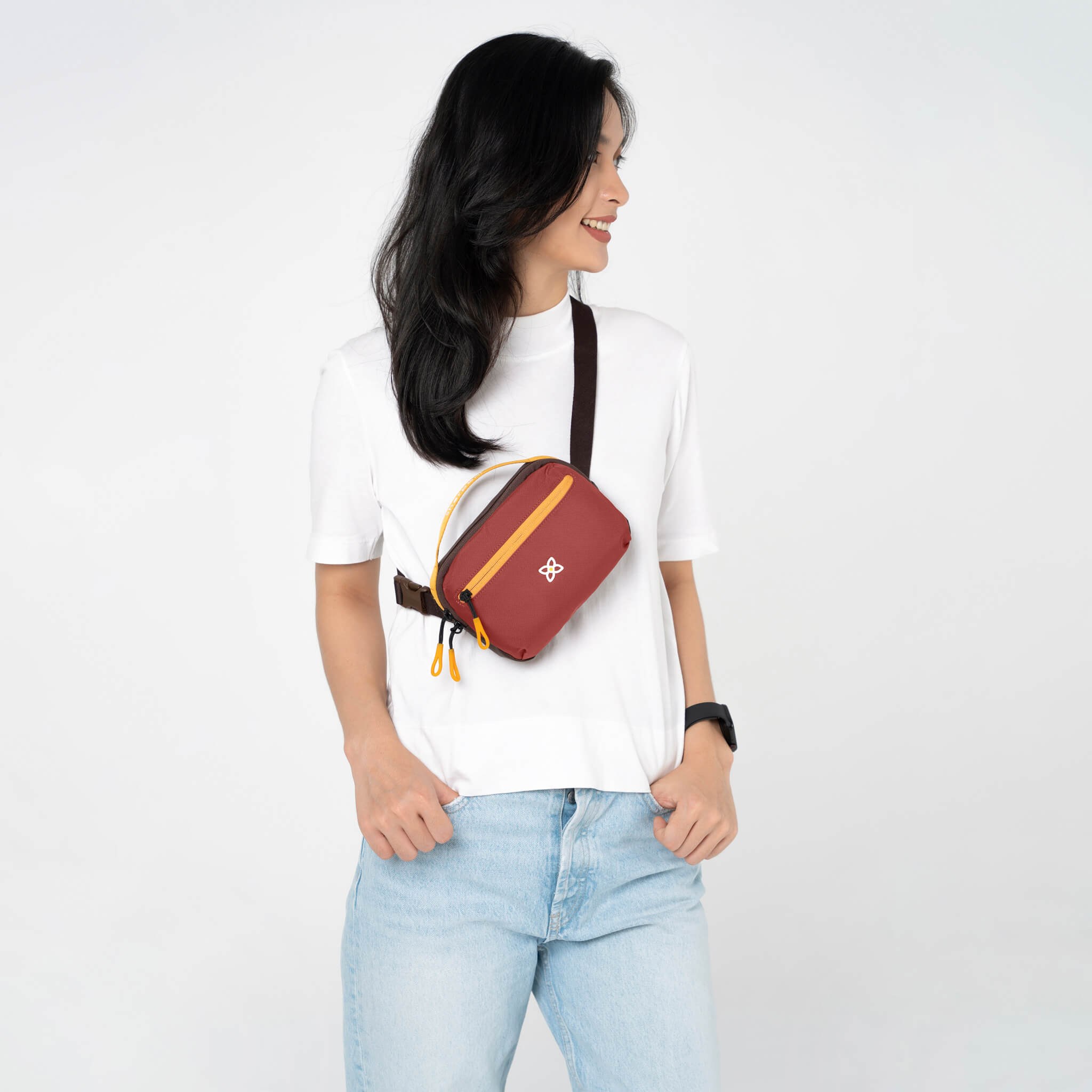A model showing Sherpani travel hip pack, the Hyk in Cider, as a small crossbody purse. 