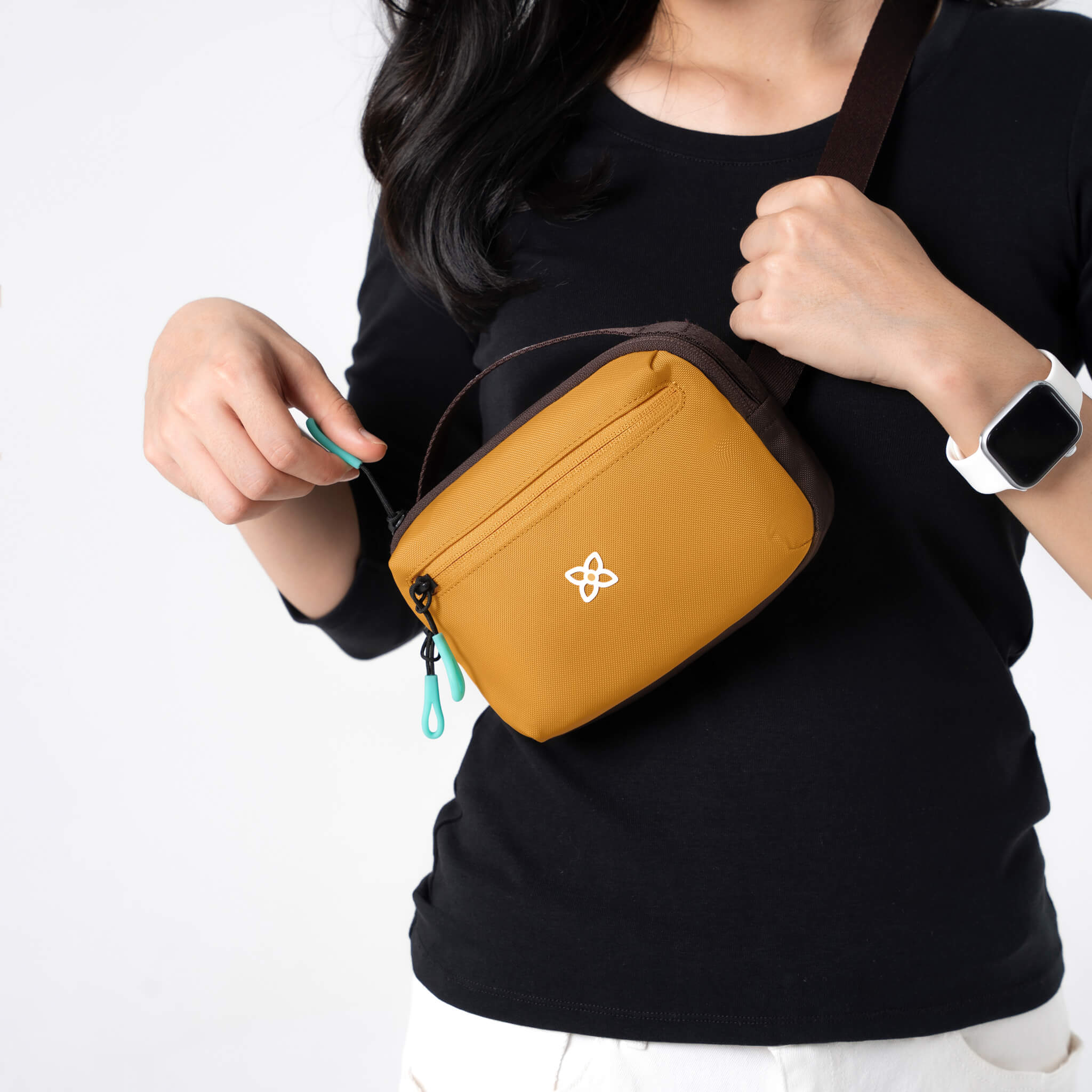 A model is wearing Sherpani belt bag, the Hyk in Sundial, as a crossbody bag. 
