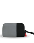 Back view of Sherpani travel accessory, the Jolie in Stone, in medium size. The pouch is two-toned in gray and black. It features a black wristlet strap and an easy-pull zipper accented in red.