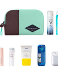 Top view of example items to fill the bag. Sherpani travel accessory, the Jolie in Seagreen in medium size, lies in the upper left corner. It is surrounded by an assortment of items: beauty products, skincare products, sunscreen, mints and AirPods.