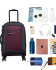 Top view of example items to fill the suitcase. On the left lies Sherpani’s Anti-Theft luggage, the Latitude in Merlot. On the right lies an assortment of items: change of clothes, sunglasses, sneakers, phone, headphones, car key, passport, water bottle, tablet, travel books and Sherpani travel accessories the Harmony in Pacific Blue and the Jolie in Sundial.