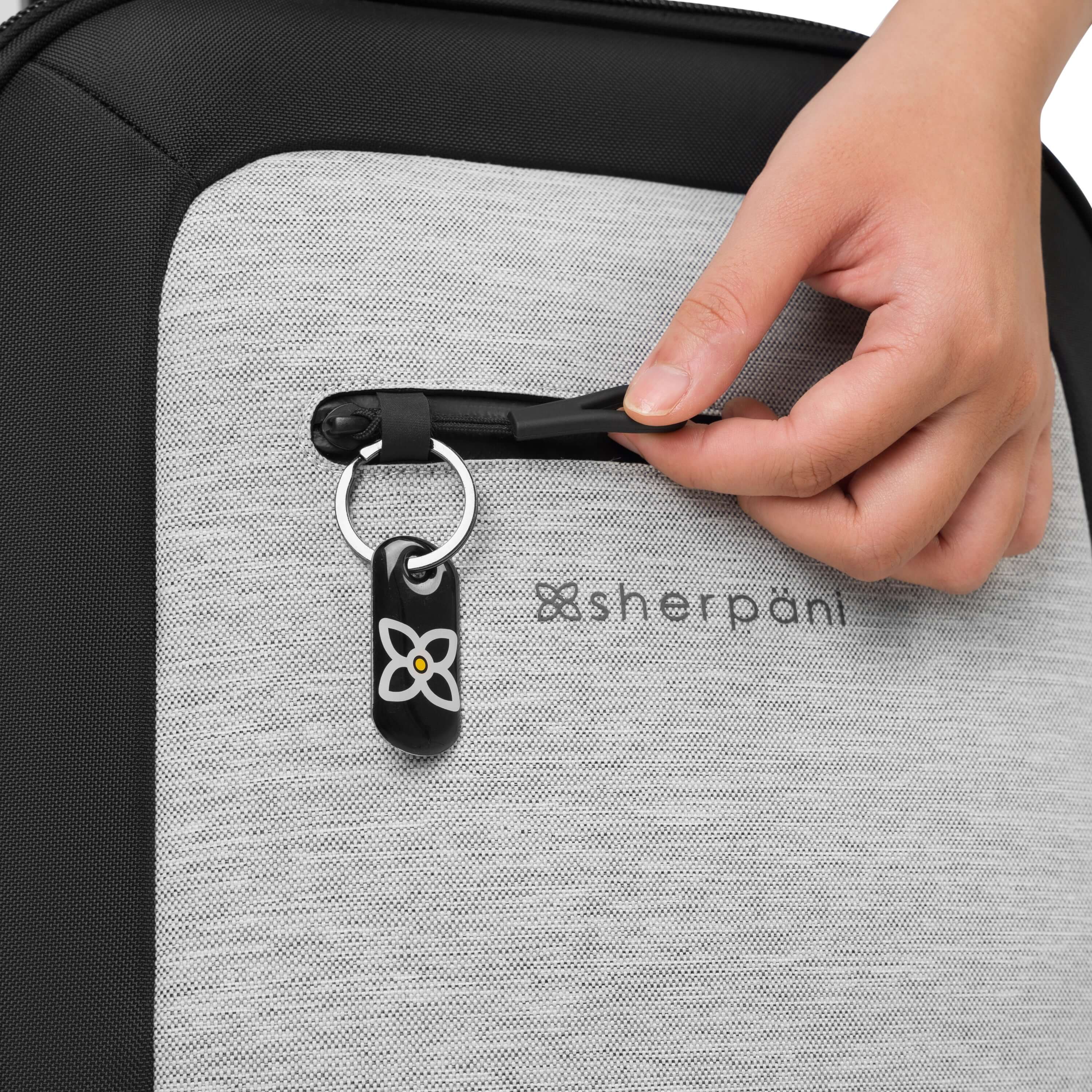 Close up view of a model's hands demonstrating the zipper lock feature on Sherpani's Anti-Theft luggage the Latitude in Sterling. 