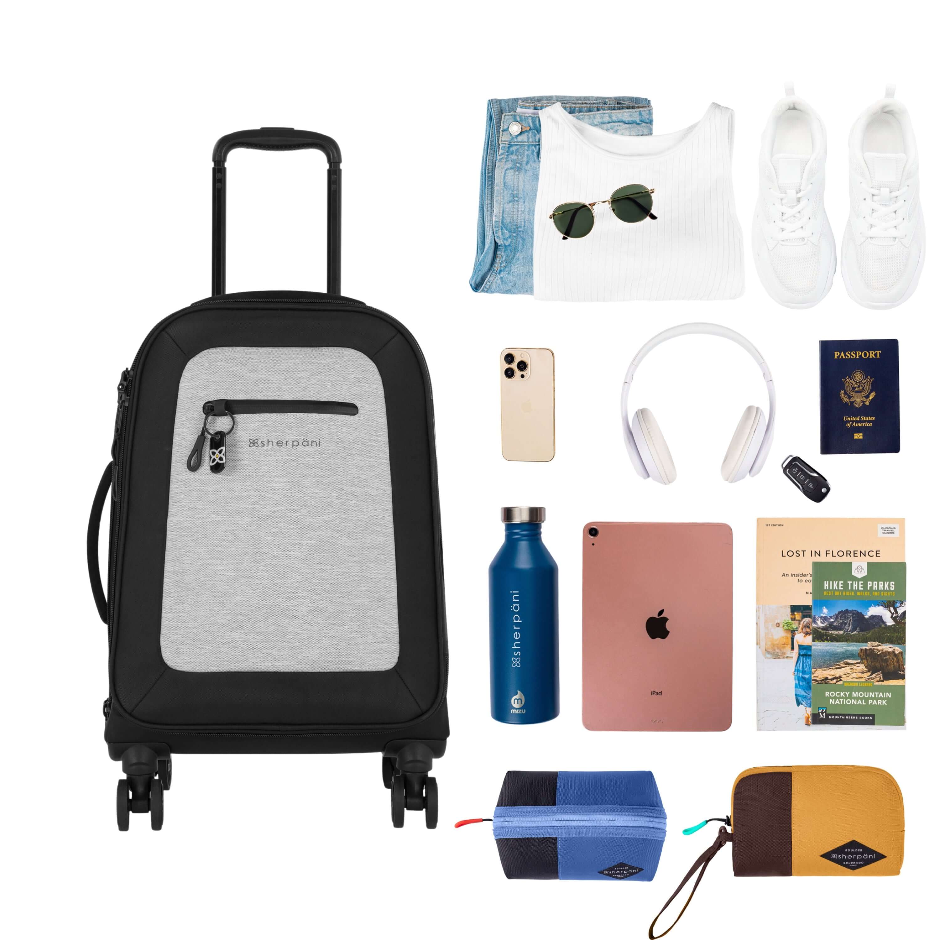 Top view of example items to fill the suitcase. On the left lies Sherpani’s Anti-Theft luggage, the Latitude in Sterling. On the right lies an assortment of items: change of clothes, sunglasses, sneakers, phone, headphones, car key, passport, water bottle, tablet, travel books and Sherpani travel accessories the Harmony in Pacific Blue and the Jolie in Sundial. 
