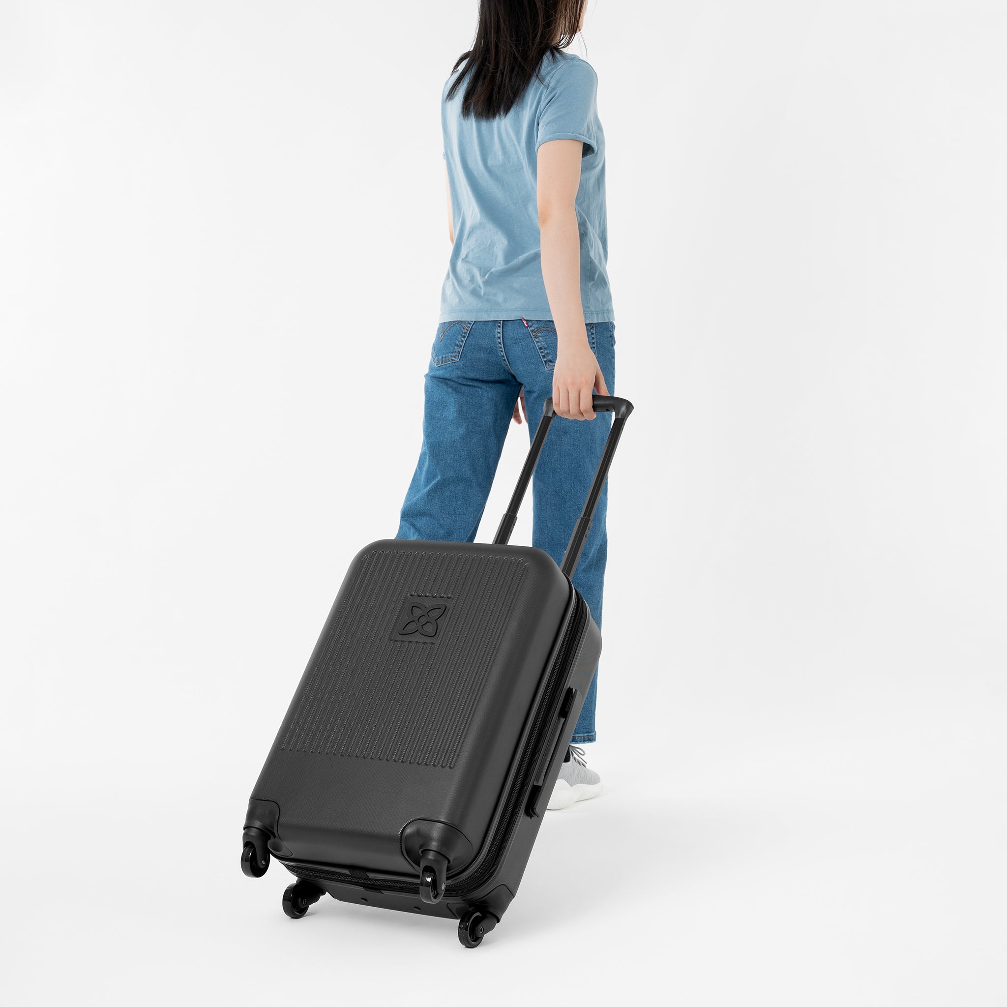 A model pulls Sherpani hard-shell luggage, the Meridian in Black, behind her. 