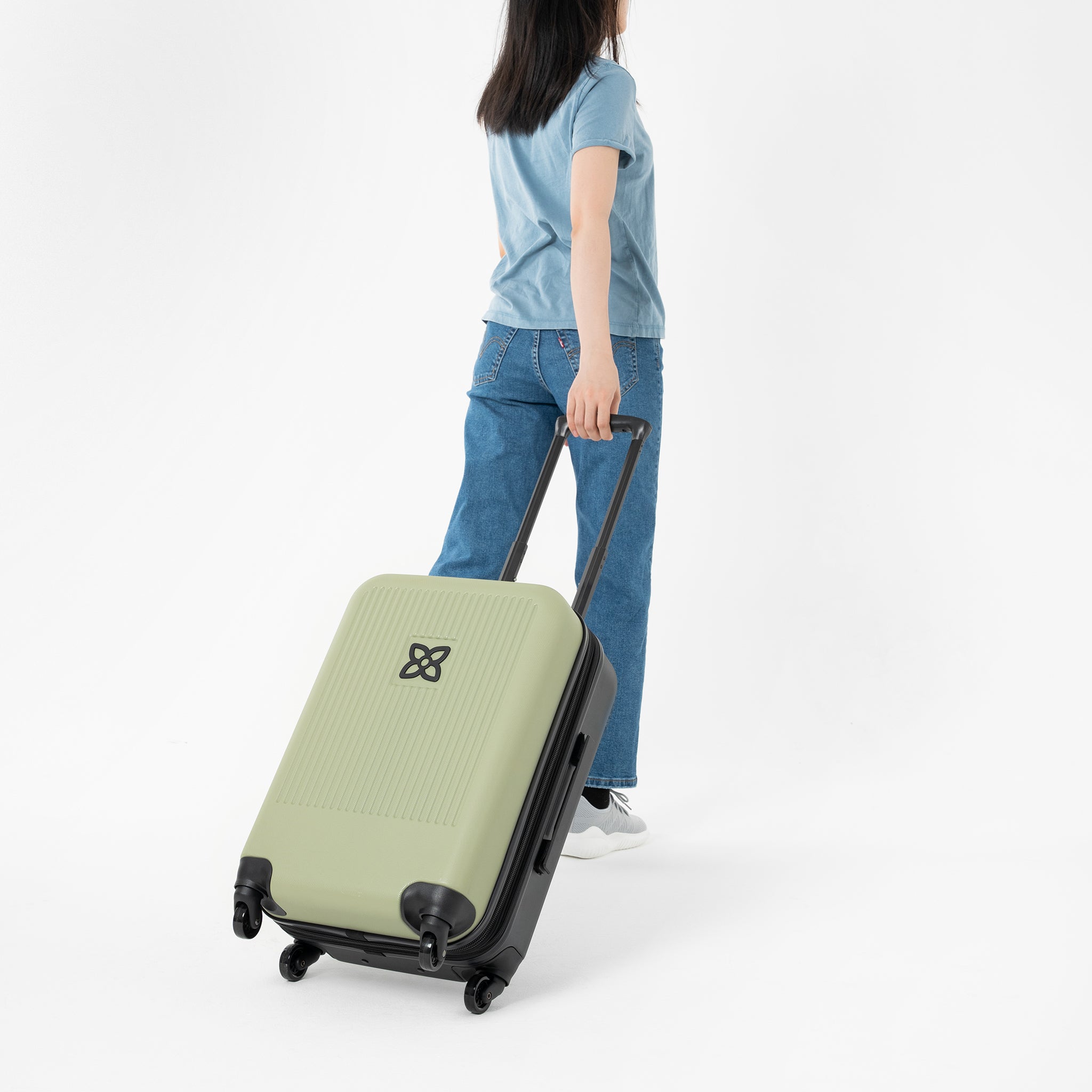 A model pulls Sherpani hard-shell luggage, the Meridian in Sage, behind her. 