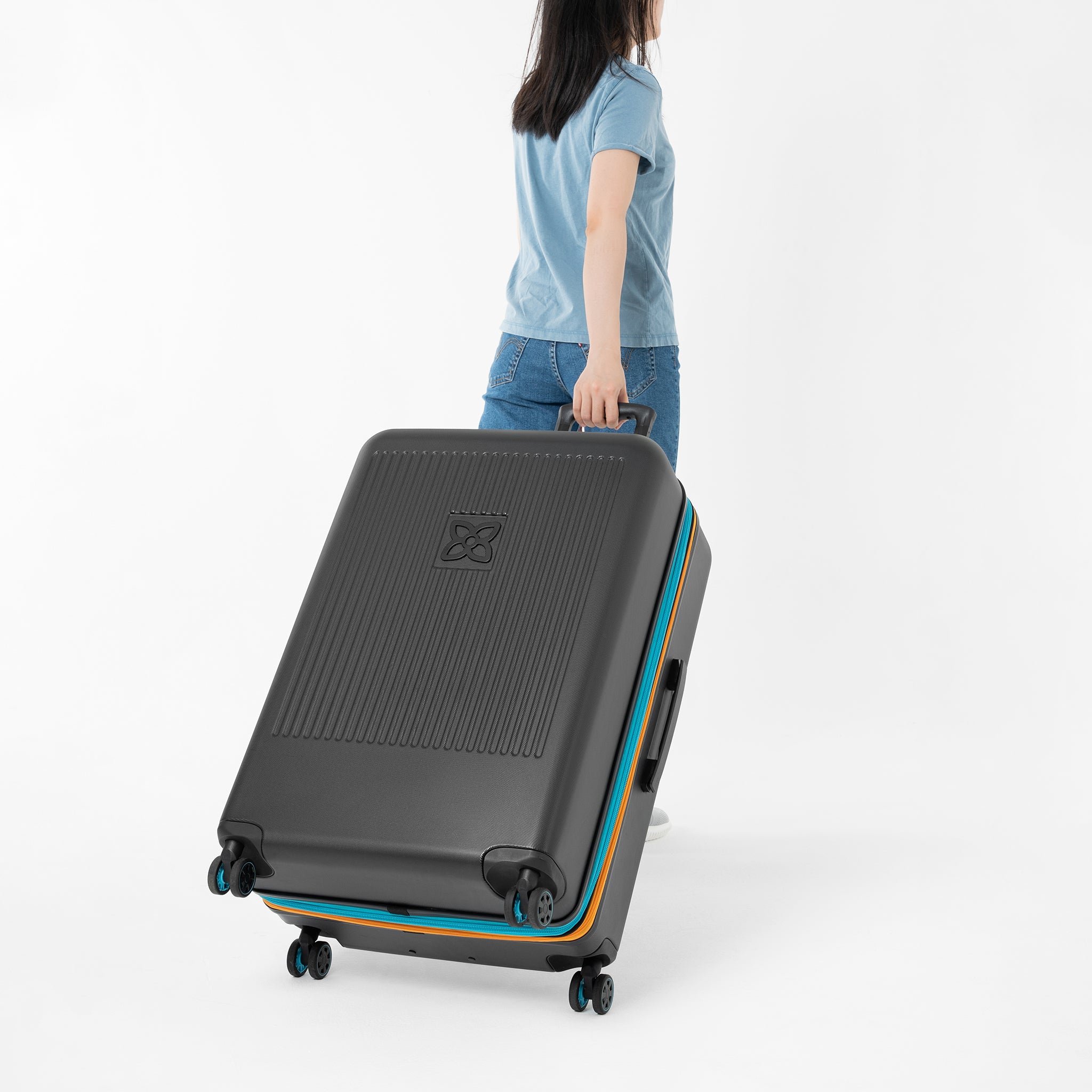 A model pulls Sherpani hard-shell luggage, the Meridian in Chromatic, behind her. 