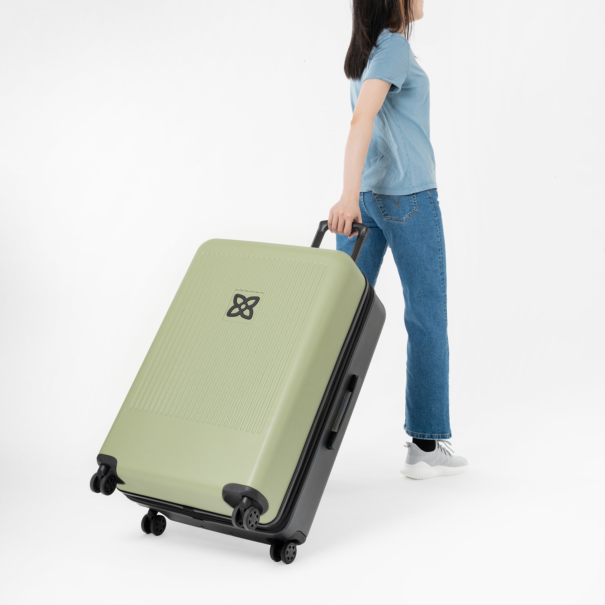 A model pulls Sherpani hard-shell luggage, the Meridian in Sage, behind her. 