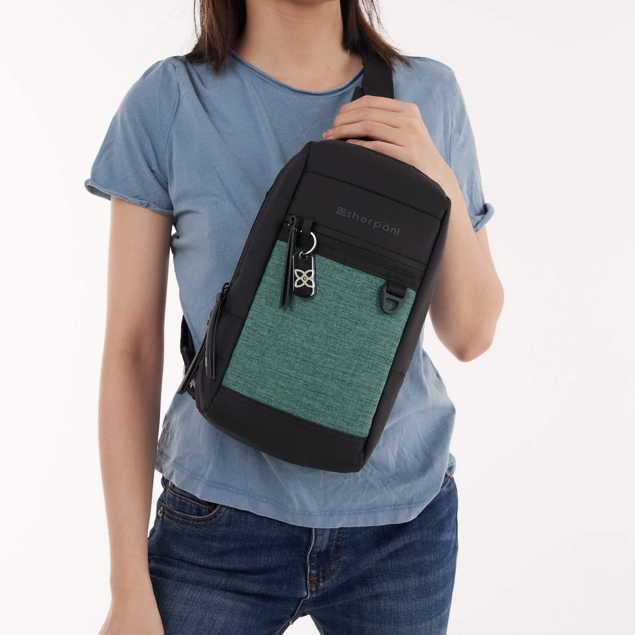 A model showing Sherpani small crossbody purse, the Metro in Teal. 