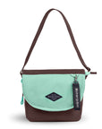 Flat front view of Sherpani crossbody, the Milli in Seagreen. The messenger style bag is two-toned: the layover flap is light green, the remainder of the bag is brown. Easy-pull zippers are accented in light green. The bag has an adjustable crossbody strap. A branded Sherpani keychain is clipped to a fabric loop in the upper right corner.