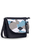 Angled front view of Sherpani crossbody, the Milli in Summer Camo. The messenger style bag is two-toned: the layover flap is a camouflage pattern of light blue, gray and white, the remainder of the bag is black. Easy-pull zippers are accented in black. The bag has an adjustable crossbody strap. A branded Sherpani keychain is clipped to a fabric loop in the upper right corner.