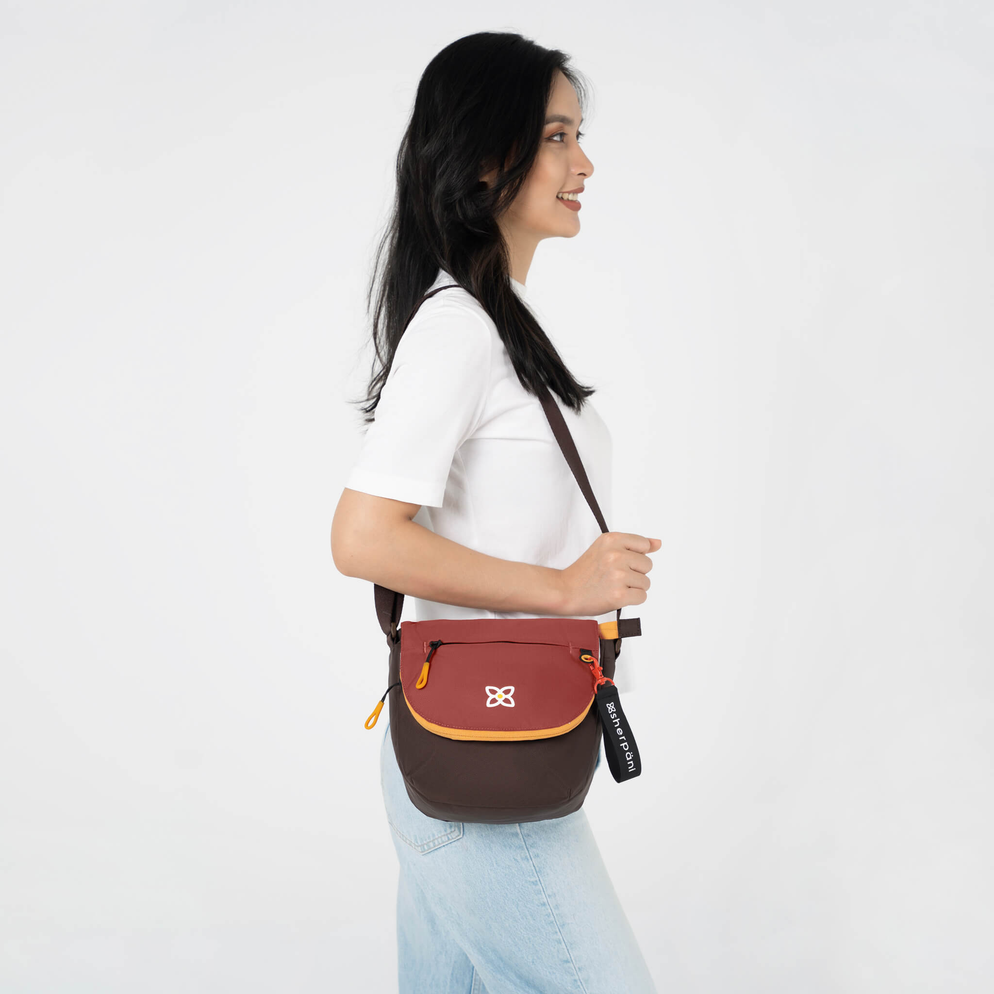A model showing Sherpani crossbody satchel purse, the Milli in Cider. 
