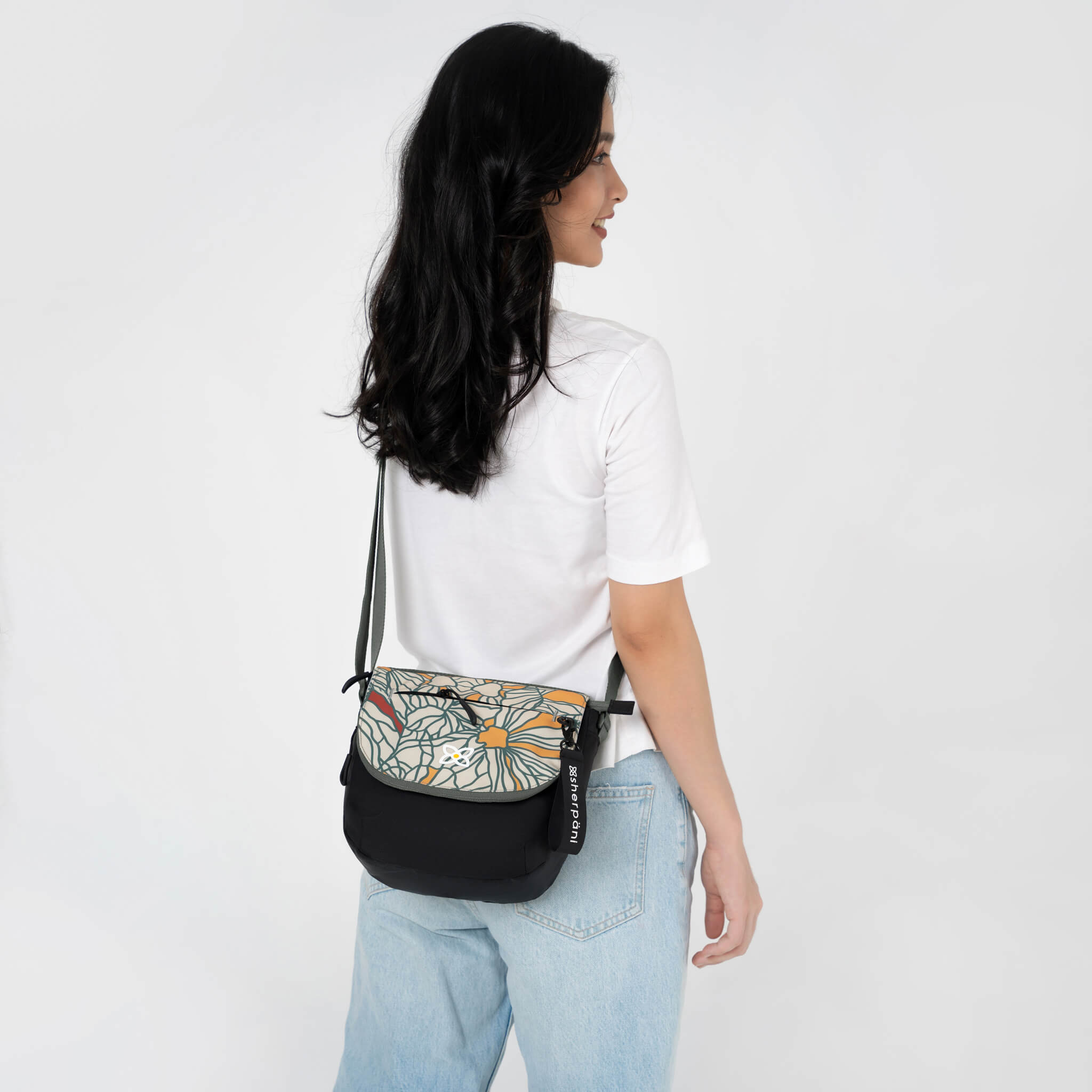 A model showing the crossbody style of Sherpani women's satchel bag, the Milli in Fiori. 