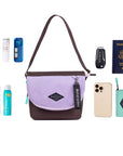 Top view of example items to fill the bag. Sherpani crossbody, the Milli in Lavender, lies in the center. It is surrounded by an assortment of items: skincare products, sunscreen, beauty spray, car key, passport, phone and Sherpani travel accessory the Barcelona in Seagreen.