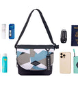 Top view of example items to fill the bag. Sherpani crossbody, the Milli in Summer Camo, lies in the center. It is surrounded by an assortment of items: skincare products, sunscreen, beauty spray, car key, passport, phone and Sherpani travel accessory the Barcelona in Seagreen.