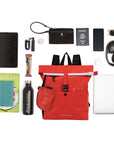 Top view of example items to fill the bag. Sherpani backpack, the Miyako in Poppy, lies in the center. It is surrounded by an assortment of items: tablet, magazine, journal, water bottle, granola bar, car key, lip balm, wallet, passport, phone, sunglasses, headphones, phone charger and laptop.