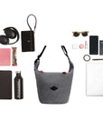 Top view of example items to fill the bag. Sherpani mesh crossbody, the Payton, lies in the center. It is surrounded by an assortment of items: water bottle, tablet, granola bar, planner, car key, headphones, wallet, sunglasses, phone charger, lib balm, hand lotion, phone, passport, hair tie, pen and laptop.