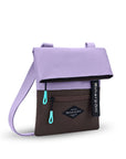 Angled front view of Sherpani crossbody, the Pica in Lavender. The bag is two toned: the top half is lavender and the bottom half is brown. There is an external zipper pocket on the front panel. Easy-pull zippers are accented in aqua. The top of the bag folds over creating a signature look. A branded Sherpani keychain is clipped to the upper right corner. The bag has an adjustable crossbody strap.