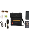 Top view of example items to fill the bag. Sherpani crossbody, the Pica in Chromatic, lies in the center. It is surrounded by an assortment of items: sunglasses, hair tie, hand lotion, gum, car key, lipstick, hairbrush, phone and passport.