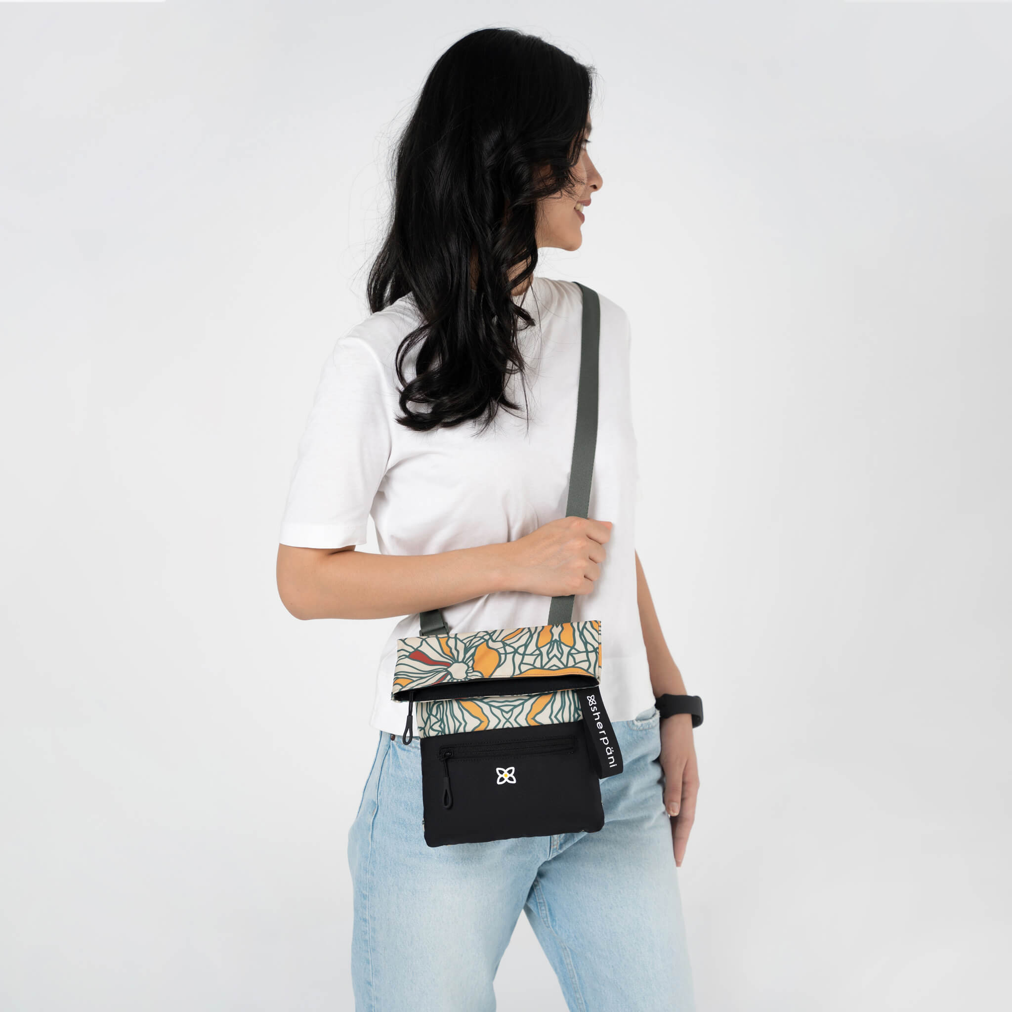 A model wearing Sherpani small crossbody travel purse, the Pica in Fiori. 
