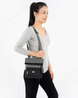 A model wearing Sherpani RFID crossbody purse, the Pica in Juniper.