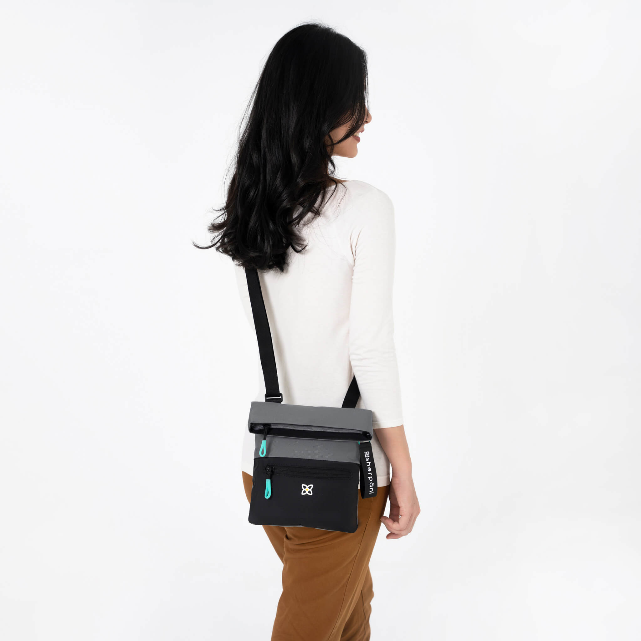 A model wearing Sherpani crossbody travel bag, the Pica in Moonstone. 