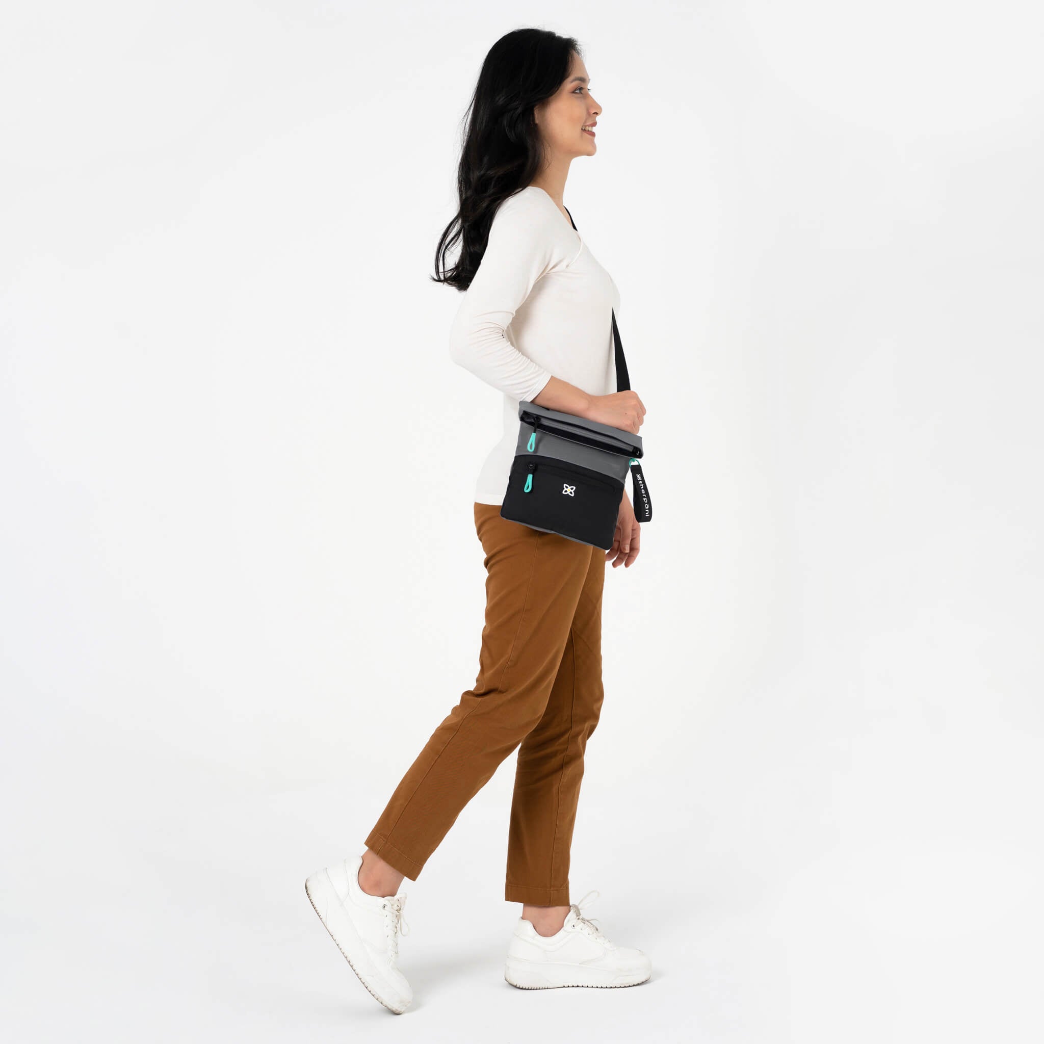 A model wearing Sherpani crossbody travel purse, the Pica in Moonstone. 