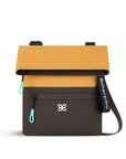 Flat front view of Sherpani fold over crossbody bag, the Pica in Sundial. Pica features include an adjustable crossbody strap, outside zipper pocket, back flap pocket, inside zipper pocket and slip pocket, detachable keychain and RFID protection. The Sundial coloway is two-toned in yellow and dark brown with turquoise accents.