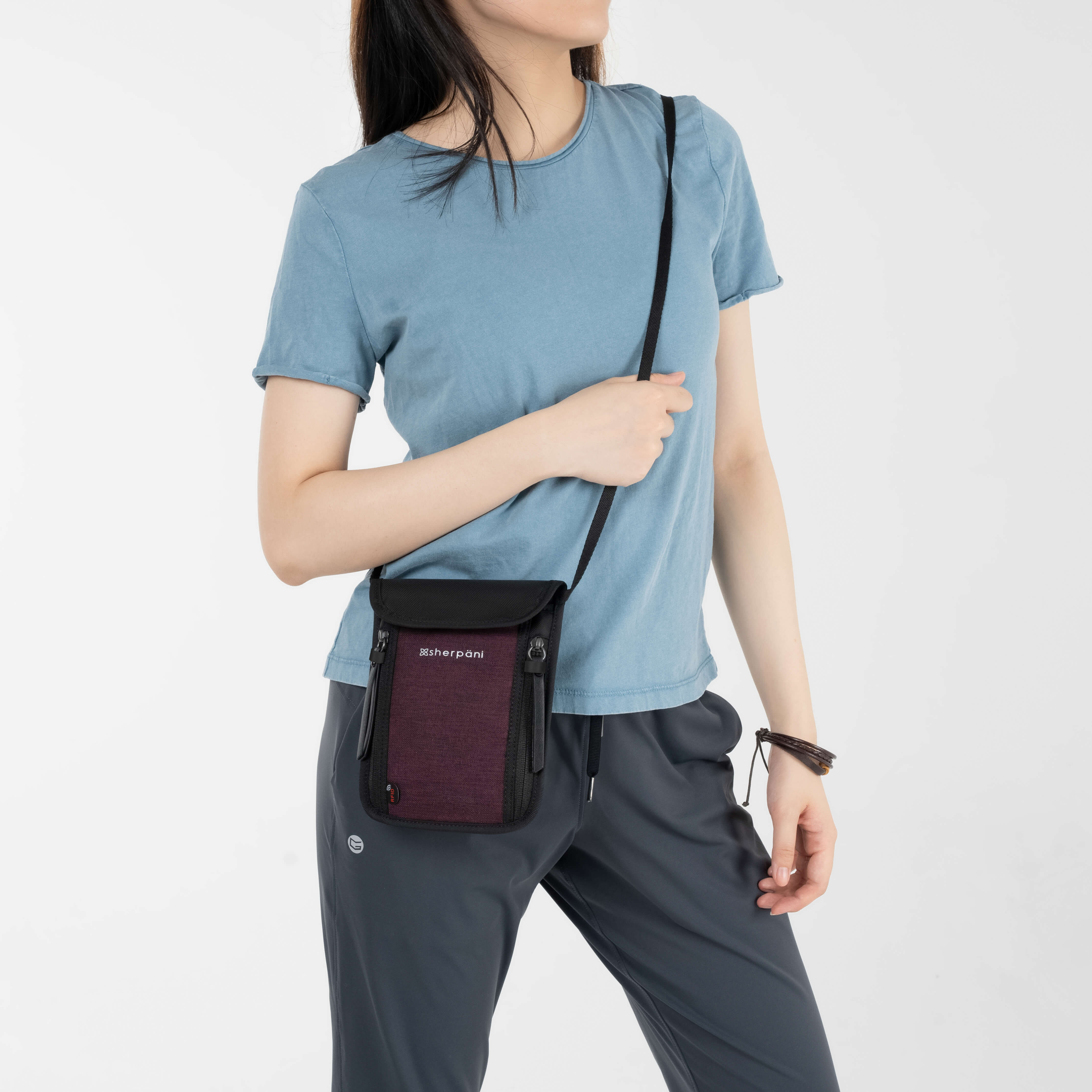 A model wearing Sherpani crossbody wallet with RFID protection and anti-theft design, the Piper in Merlot. 