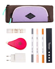 Top view of example items to fill the pouch. Sherpani travel accessory, the Poet in Lavender, lies at the top. Below it are an assortment of items: glue stick, white out, phone charger, markers.