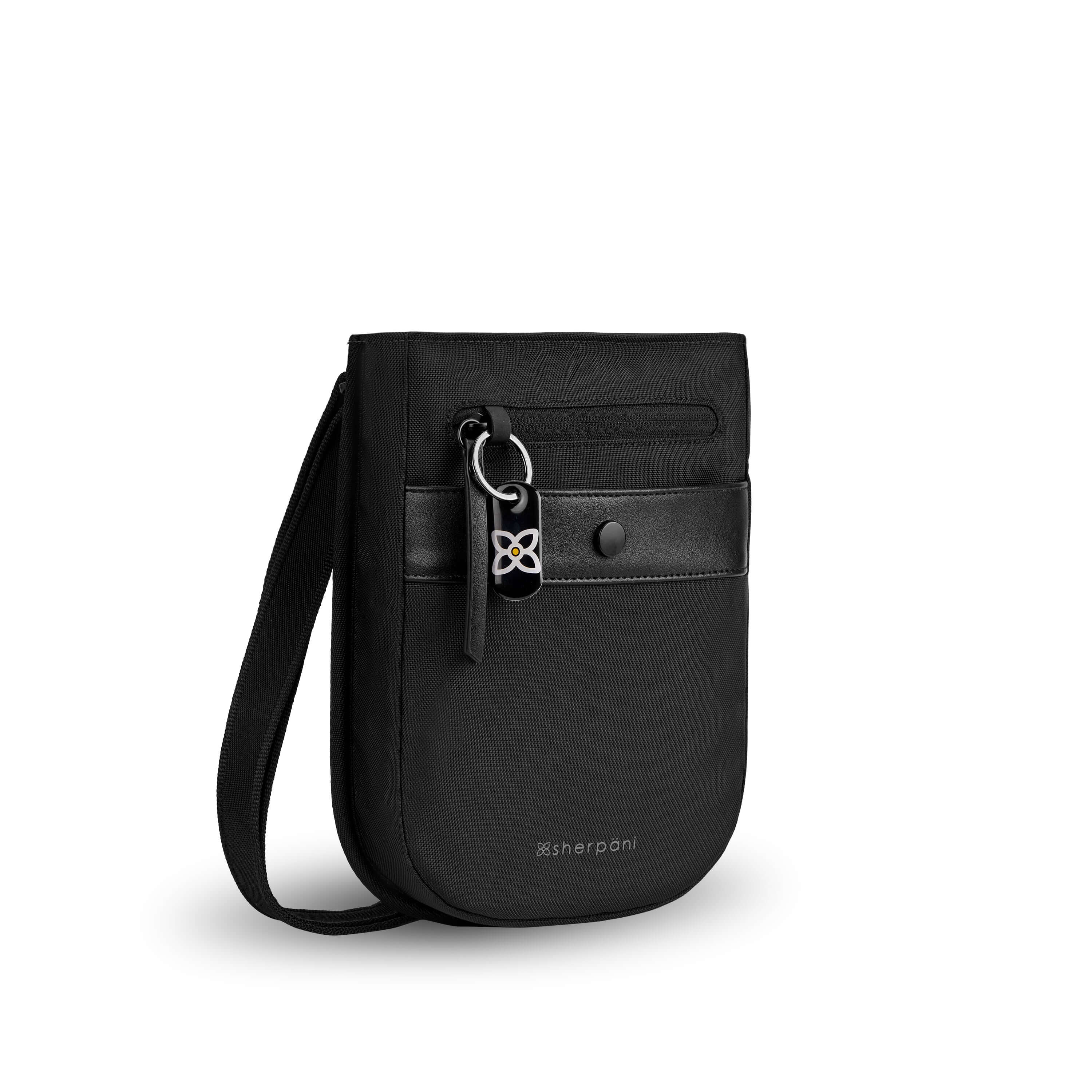Angled front view of Sherpani’s Anti-Theft bag, the Prima AT in Carbon, with vegan leather accents in black. There is an external pouch on the front of the bag that sits below a locking zipper compartment, which has a ReturnMe tag clipped to it. The bag features an adjustable crossbody strap. #color_carbon
