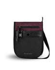 Flat front view of Sherpani’s Anti-Theft bag, the Prima AT in Merlot, with vegan leather accents in black. There is an external pouch on the front of the bag that sits below a locking zipper compartment, which has a ReturnMe tag clipped to it. The bag features an adjustable crossbody strap.